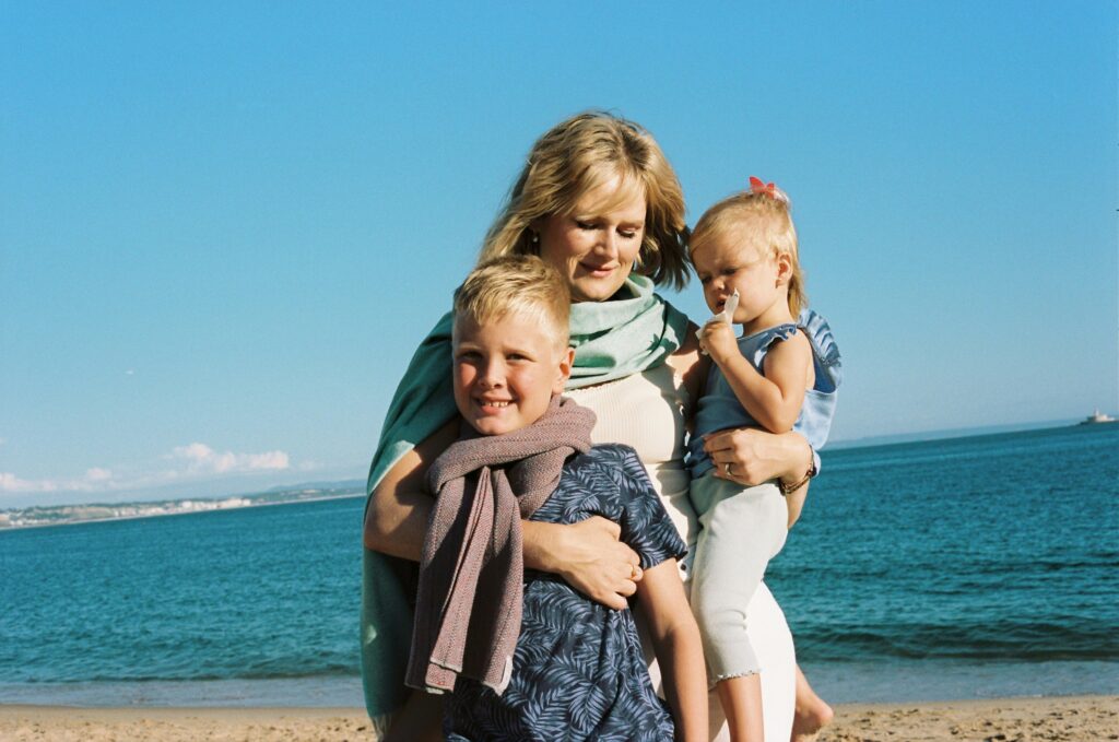 A woman embraces her two children on a beach, representing the emotional heart of estate planning. The image underscores the role of trusts in safeguarding family stability and passing on wealth with care.