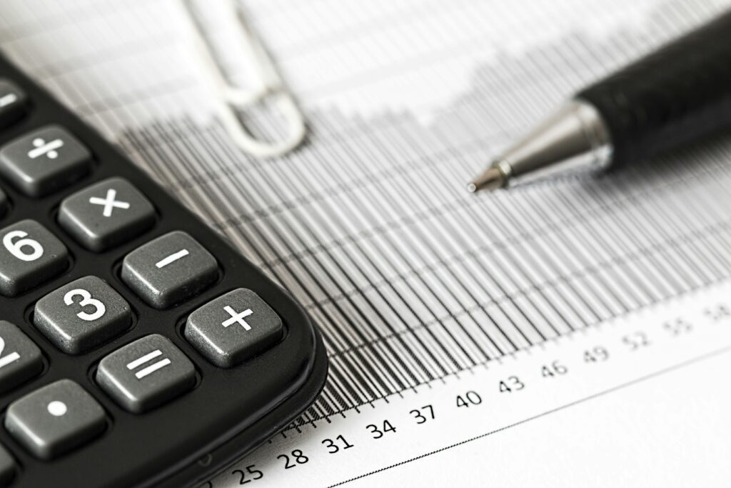 An image showing a calculator and pen on a table against tax forms.