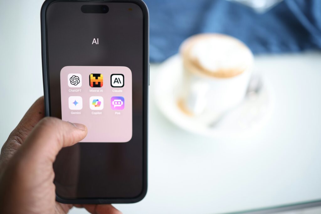 A person holding a cell phone featuring AI apps in their hand, symbolizing the integration of technology in tax compliance and audits.