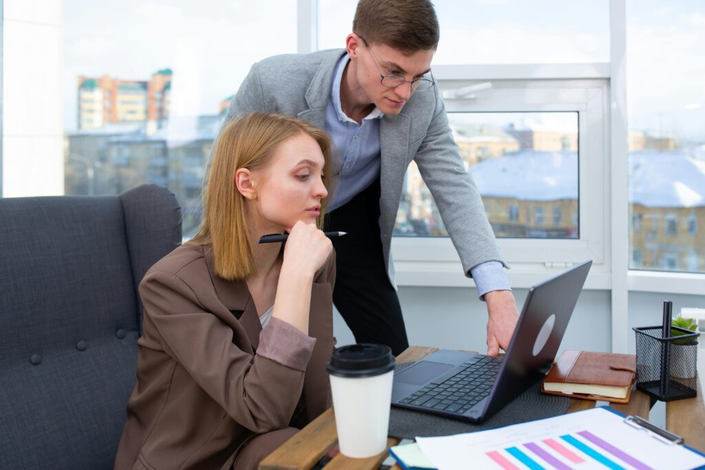 A man and woman sitting together, reviewing something on a laptop—representing clients discussing personalized tax strategies with their financial advisor.