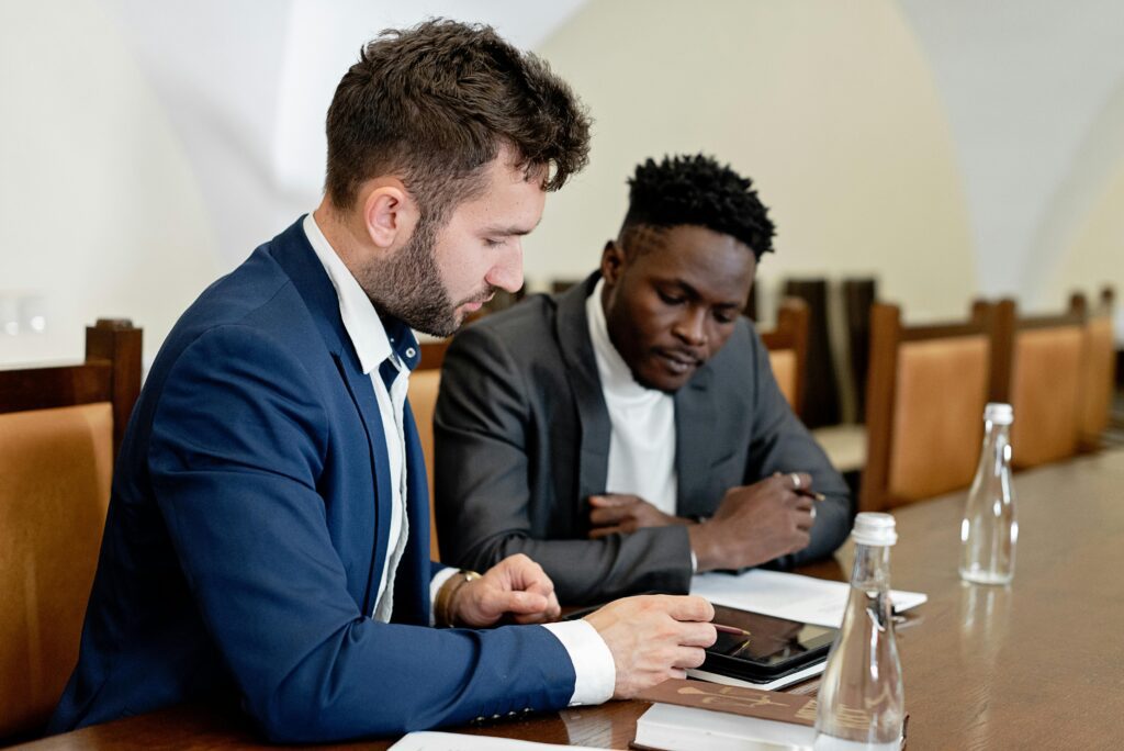 Two business professionals in a meeting, attentively listening and taking notes—reflecting the strategic conversations financial advisors have when weighing the tax advantages of asset location versus allocation. Link: https://www.pexels.com/photo/businessmen-in-a-meeting-8729815/