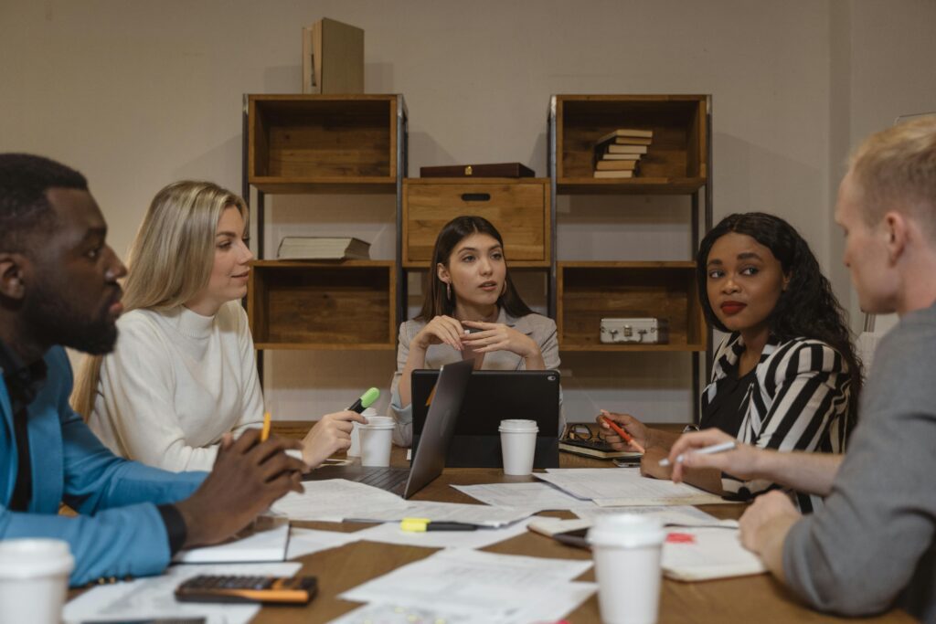 A diverse group of professionals seated around a long conference table, engaged in a focused meeting under soft overhead lighting—evoking strategic discussion and collaborative financial planning.