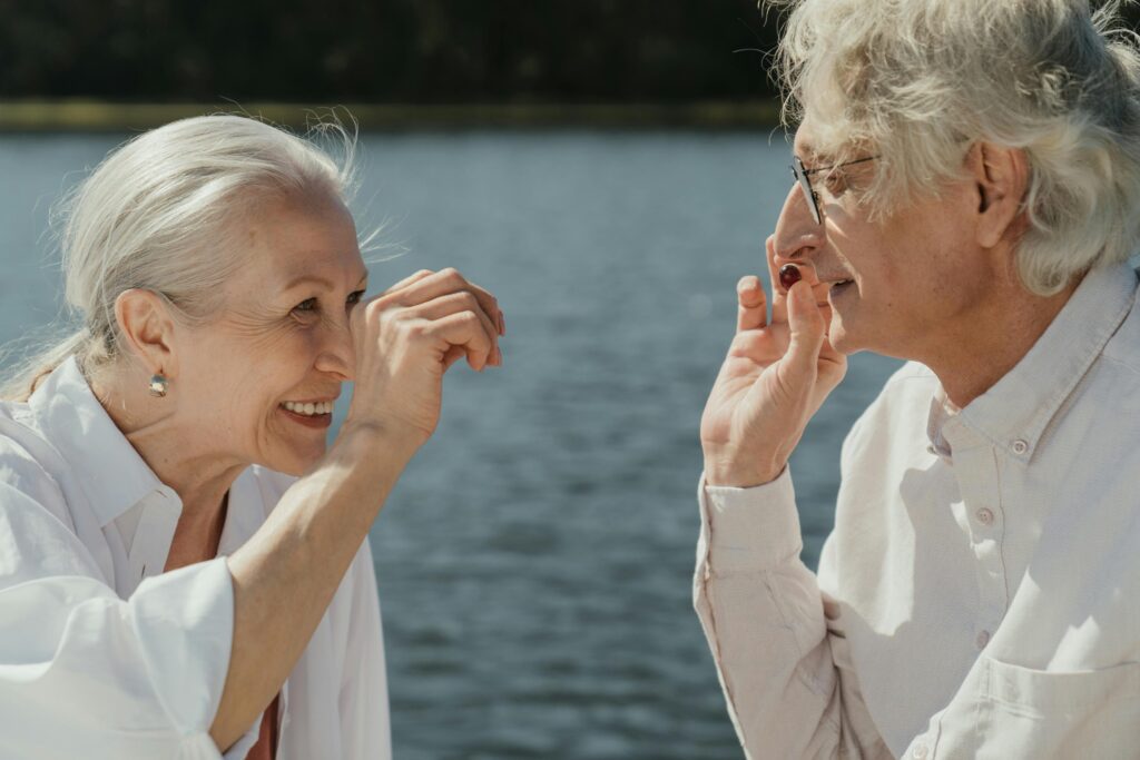 Two elderly individuals smiling warmly at each other, capturing a moment of connection and shared happiness.