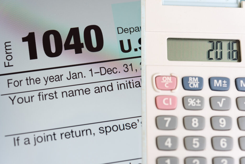 Image of 1040 next to a calculator to symbolize tax filing.