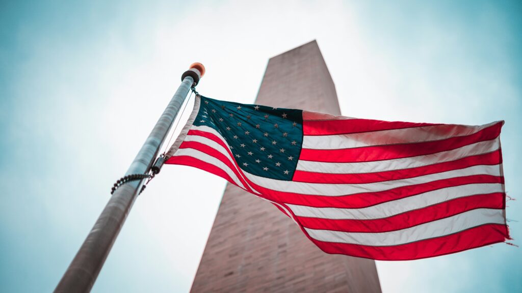Image of the Washington Monument with a US flag in front.