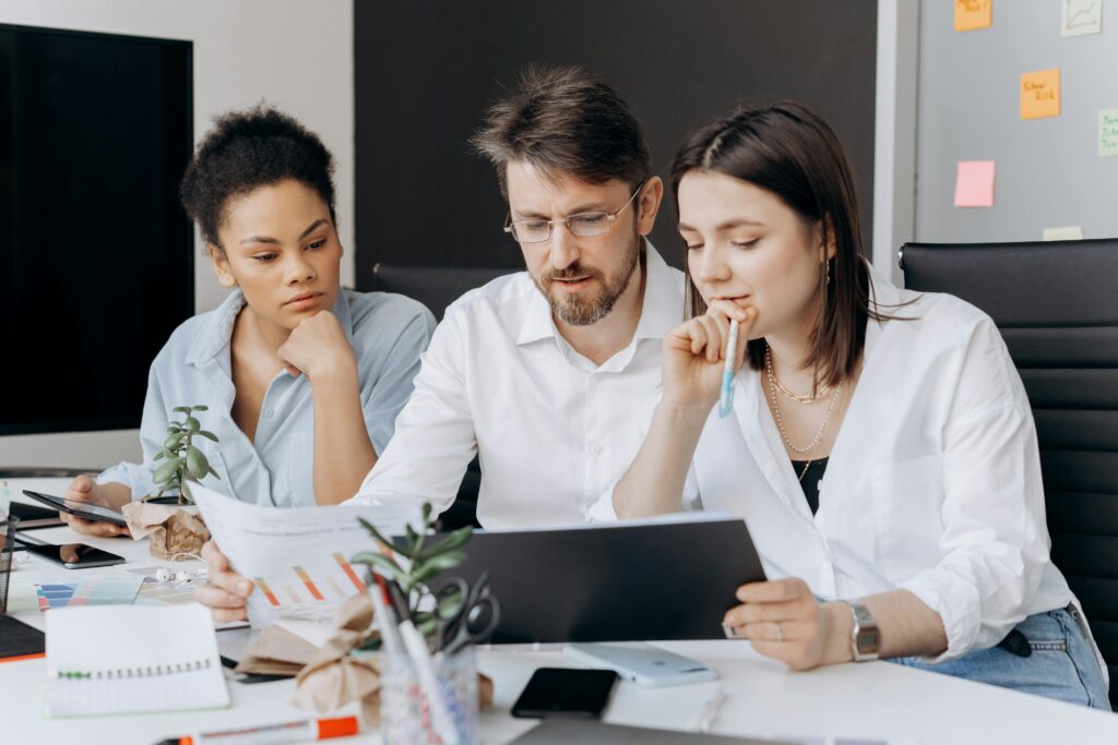 A group of office colleagues sitting around a table, engaged in a discussion on strategies for running an efficient tax firm.