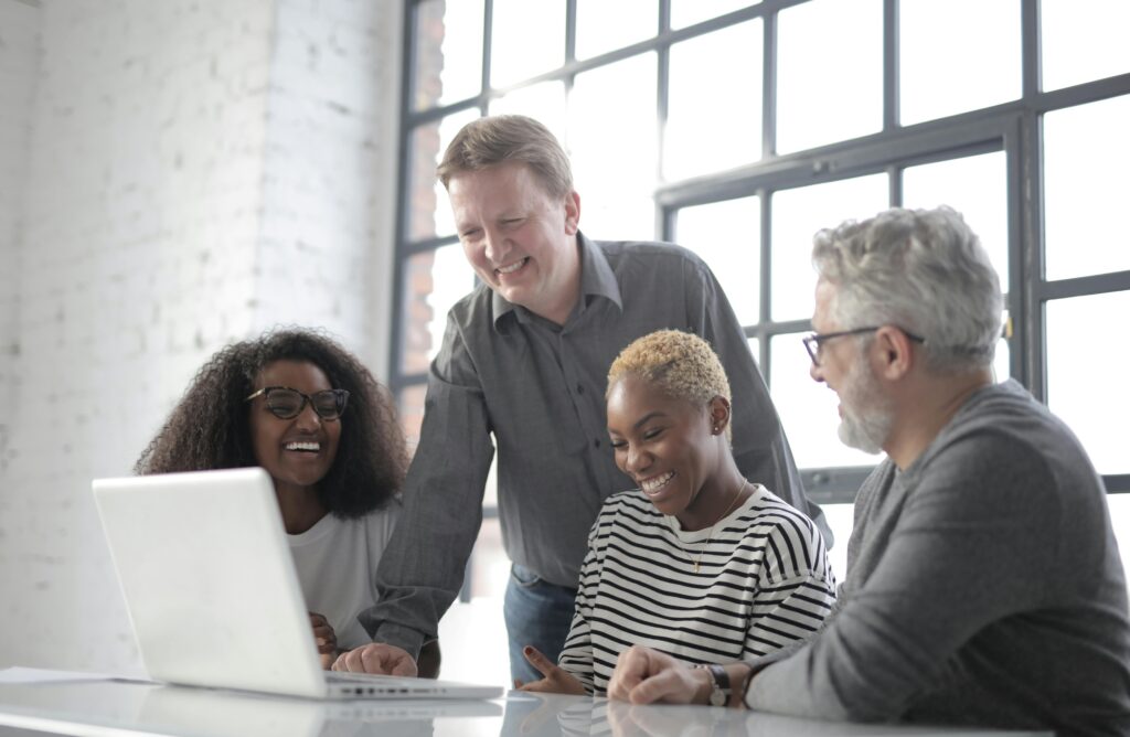 Smiling colleagues surfing a laptop in a creative office.